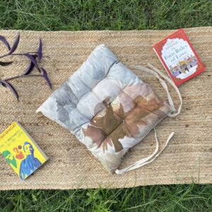 Upcycled chair pad made from repurposed fabrics placed on a mat with books – eco-friendly handmade cushion for sustainable home décor.