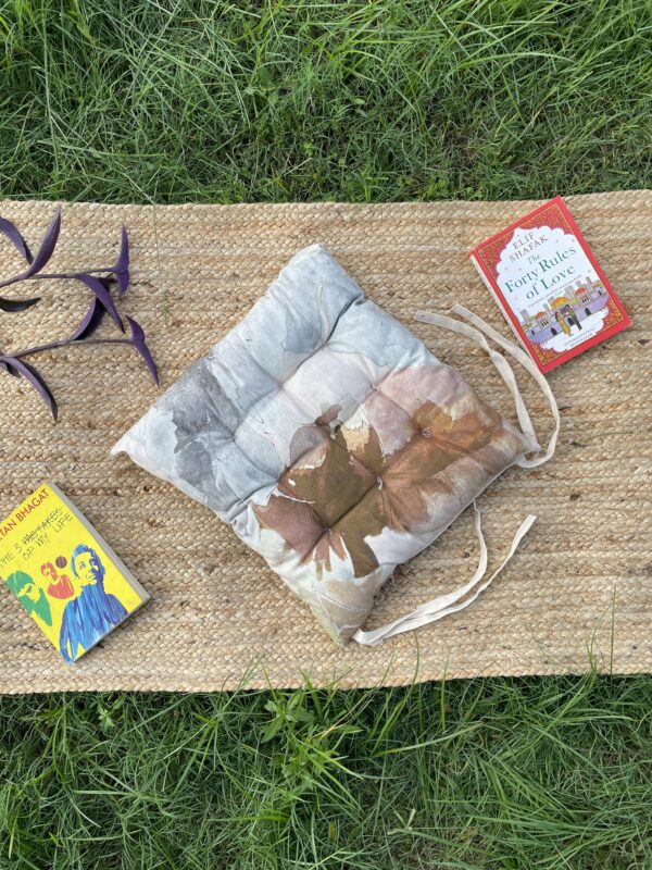 Upcycled chair pad made from repurposed fabrics placed on a mat with books – eco-friendly handmade cushion for sustainable home décor.