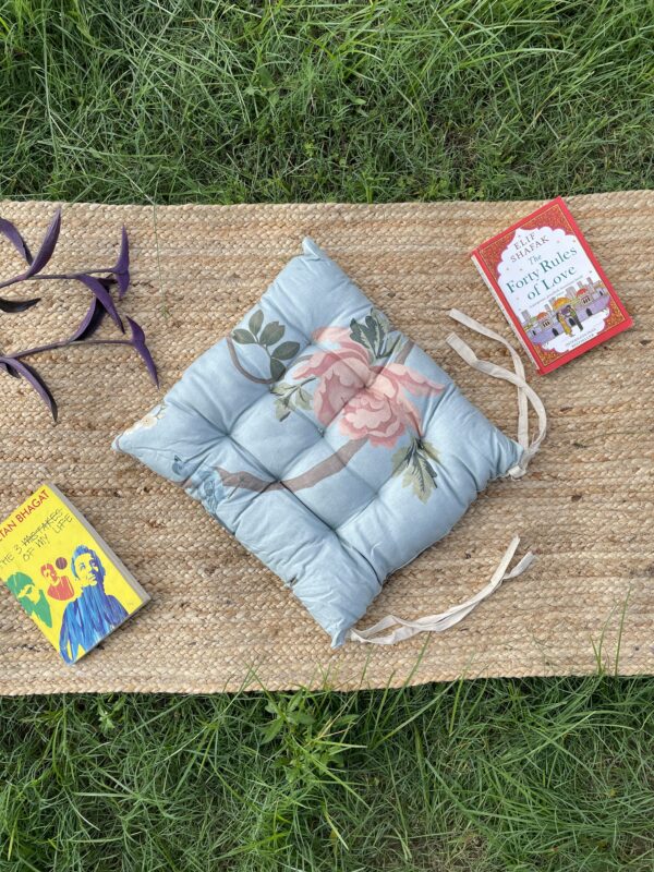 Upcycled chair pad made from repurposed fabrics placed on a mat with books – eco-friendly handmade cushion for sustainable home décor.