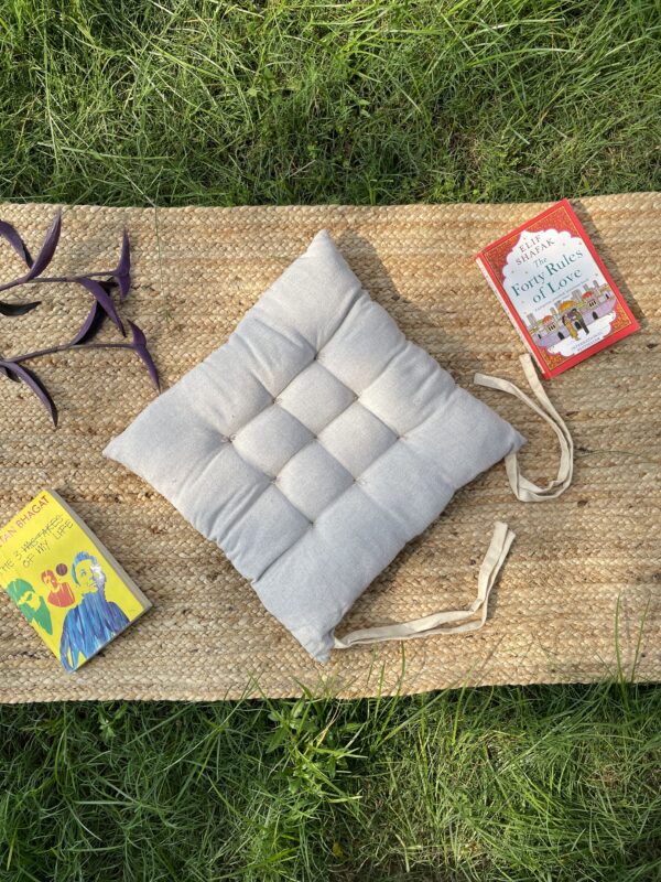 Upcycled chair pad made from repurposed fabrics placed on a mat with books – eco-friendly handmade cushion for sustainable home décor.