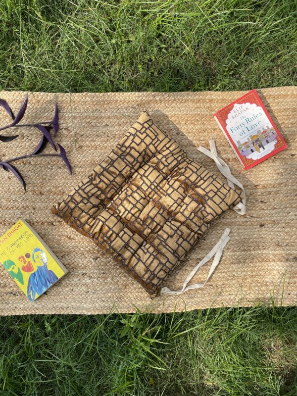 Upcycled chair pad made from repurposed fabrics placed on a mat with books – eco-friendly handmade cushion for sustainable home décor.