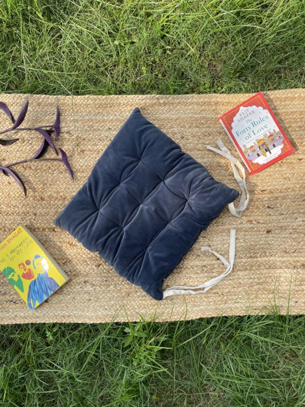 Upcycled chair pad made from repurposed fabrics placed on a mat with books – eco-friendly handmade cushion for sustainable home décor.