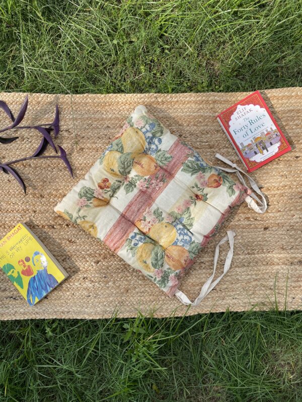 Upcycled chair pad made from repurposed fabrics placed on a mat with books – eco-friendly handmade cushion for sustainable home décor.