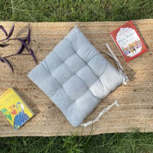 Upcycled chair pad made from repurposed fabrics placed on a mat with books – eco-friendly handmade cushion for sustainable home décor.