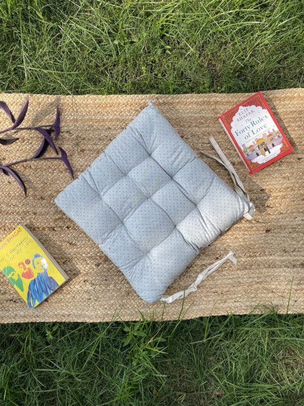 Upcycled chair pad made from repurposed fabrics placed on a mat with books – eco-friendly handmade cushion for sustainable home décor.