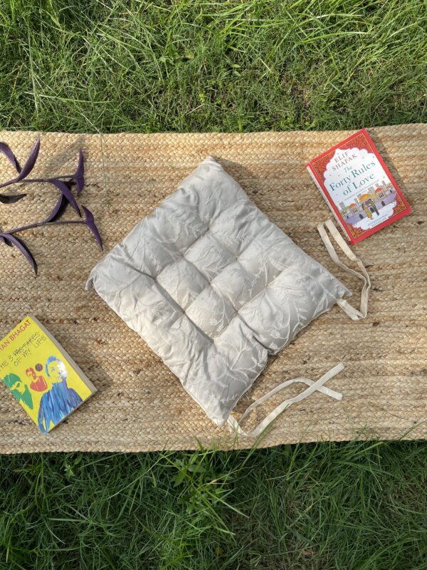 Upcycled chair pad made from repurposed fabrics placed on a mat with books – eco-friendly handmade cushion for sustainable home décor.