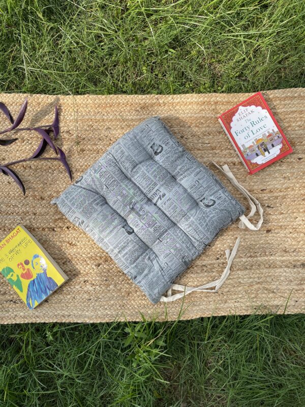 Upcycled chair pad made from repurposed fabrics placed on a mat with books – eco-friendly handmade cushion for sustainable home décor.