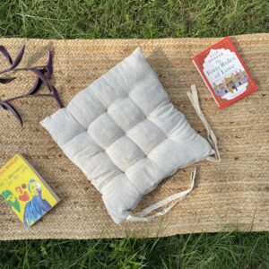 Upcycled chair pad made from repurposed fabrics placed on a mat with books – eco-friendly handmade cushion for sustainable home décor.