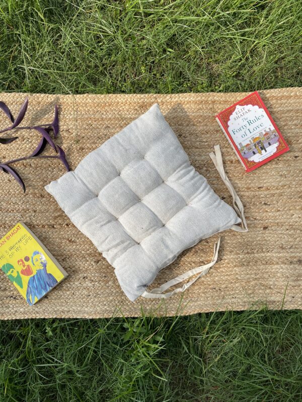 Upcycled chair pad made from repurposed fabrics placed on a mat with books – eco-friendly handmade cushion for sustainable home décor.