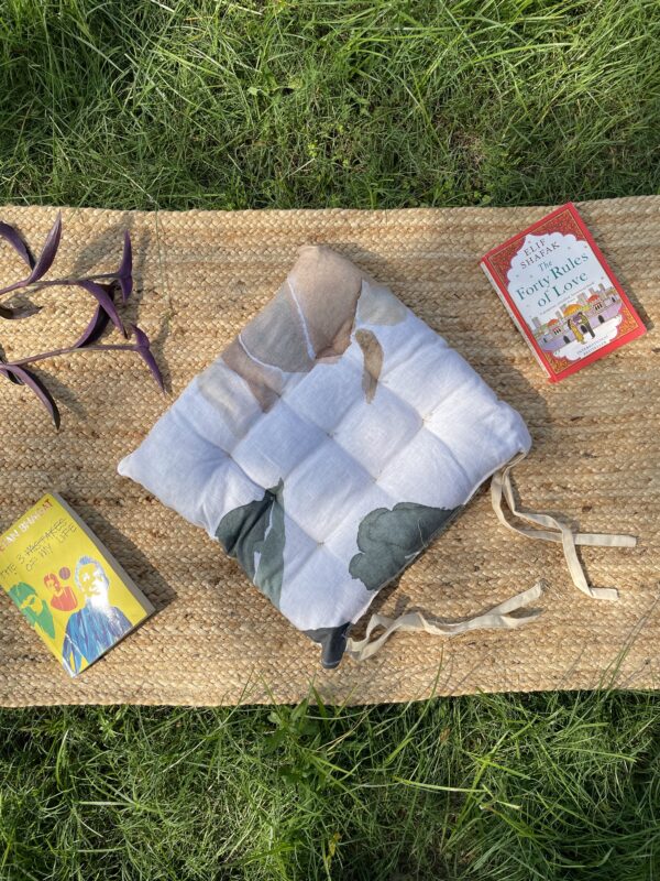 Upcycled chair pad made from repurposed fabrics placed on a mat with books – eco-friendly handmade cushion for sustainable home décor.