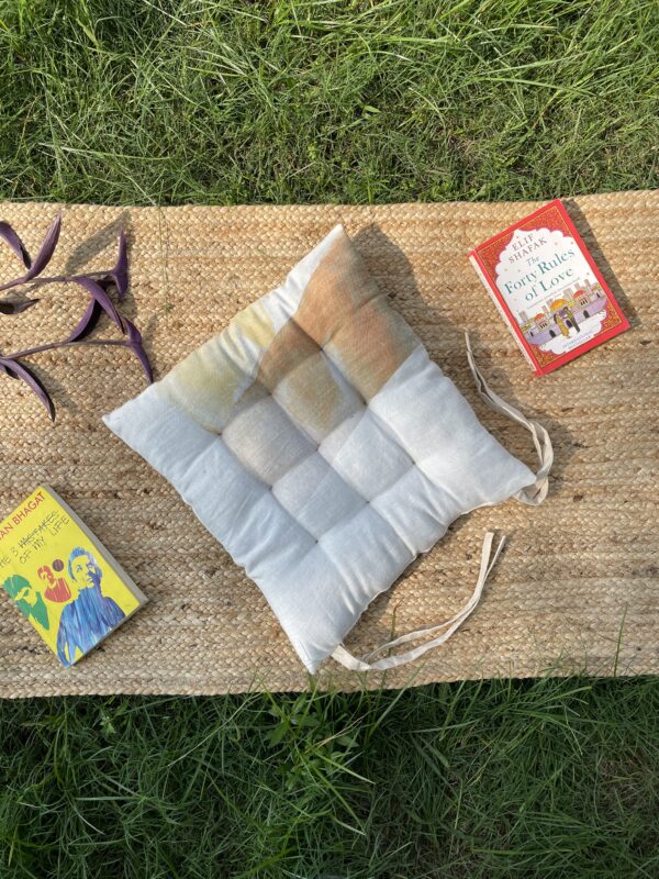 Upcycled chair pad made from repurposed fabrics placed on a mat with books – eco-friendly handmade cushion for sustainable home décor.
