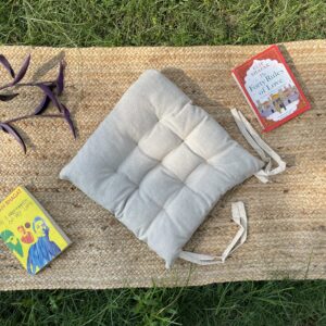 Upcycled chair pad made from repurposed fabrics placed on a mat with books – eco-friendly handmade cushion for sustainable home décor.