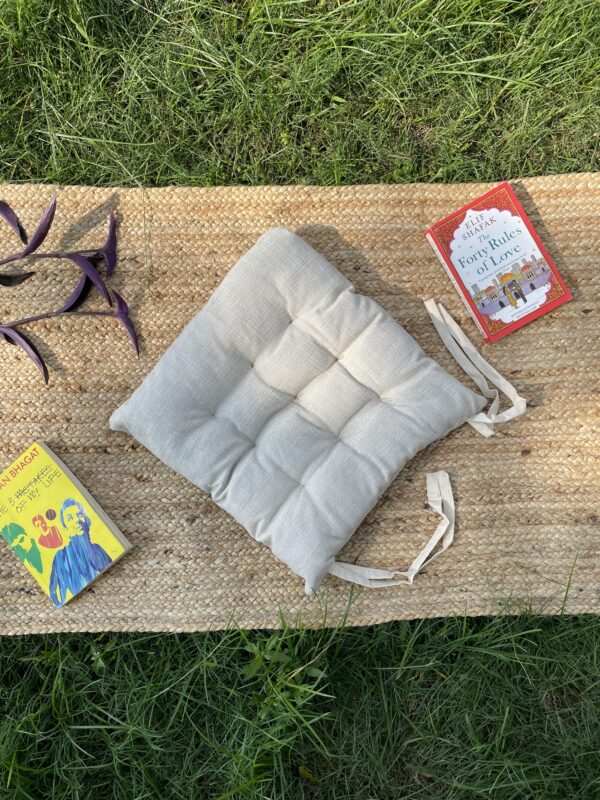 Upcycled chair pad made from repurposed fabrics placed on a mat with books – eco-friendly handmade cushion for sustainable home décor.