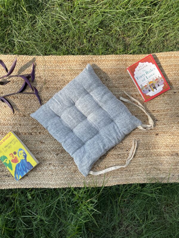 Upcycled chair pad made from repurposed fabrics placed on a mat with books – eco-friendly handmade cushion for sustainable home décor.
