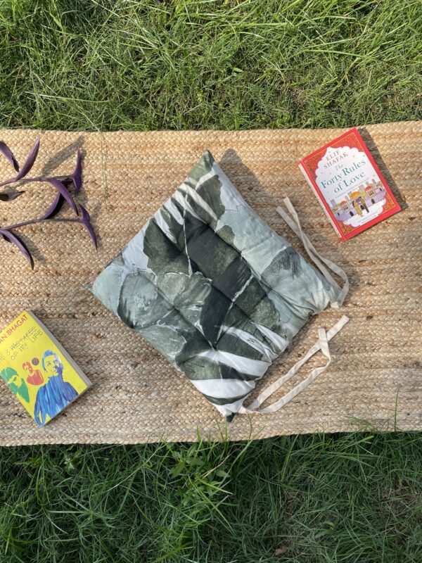 Upcycled chair pad made from repurposed fabrics placed on a mat with books – eco-friendly handmade cushion for sustainable home décor.