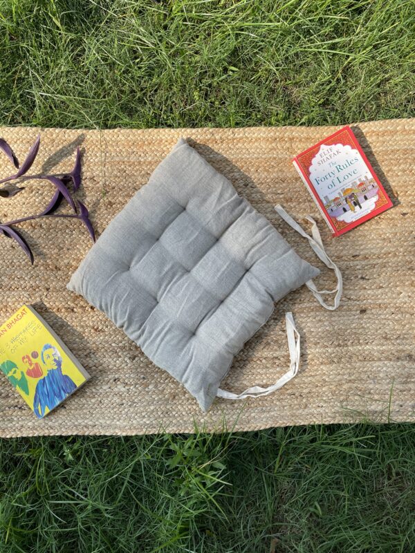 Upcycled chair pad made from repurposed fabrics placed on a mat with books – eco-friendly handmade cushion for sustainable home décor.