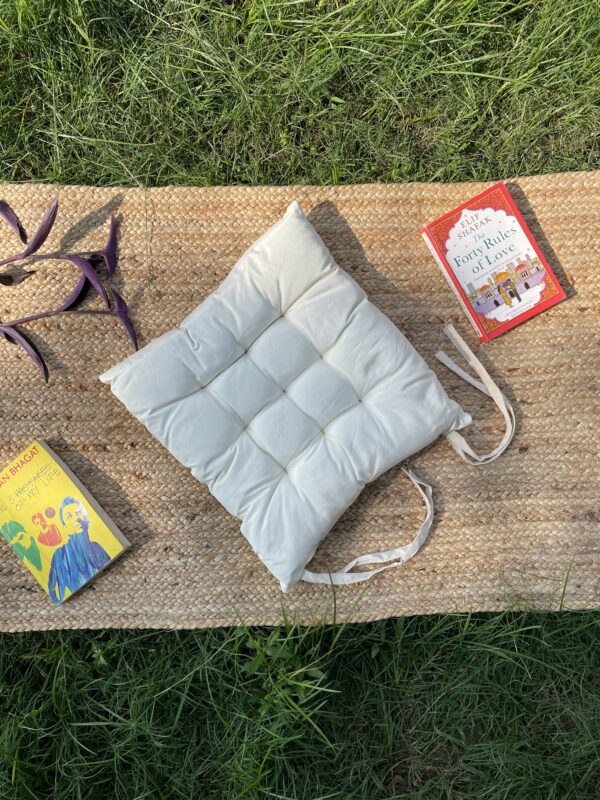 Upcycled chair pad made from repurposed fabrics placed on a mat with books – eco-friendly handmade cushion for sustainable home décor.