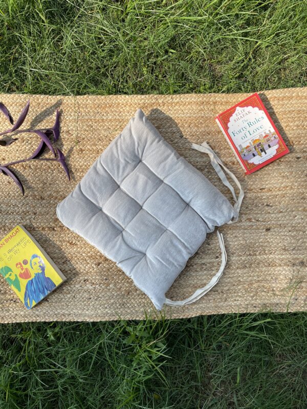 Upcycled chair pad made from repurposed fabrics placed on a mat with books – eco-friendly handmade cushion for sustainable home décor.
