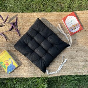 Upcycled chair pad made from repurposed fabrics placed on a mat with books – eco-friendly handmade cushion for sustainable home décor.