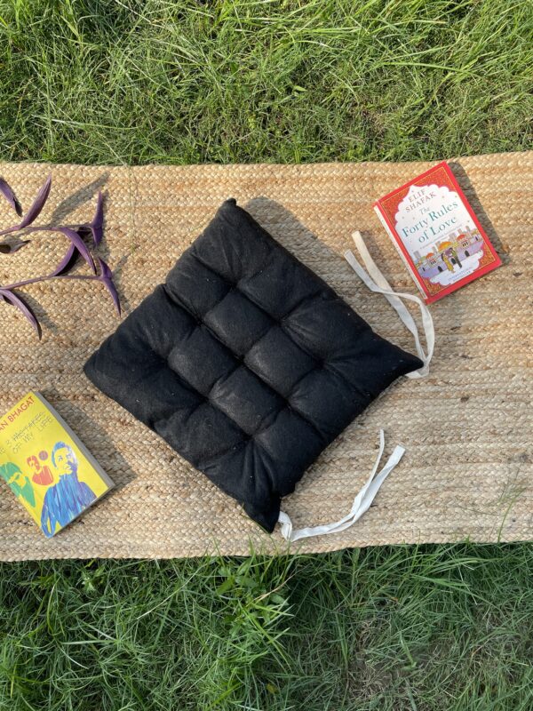 Upcycled chair pad made from repurposed fabrics placed on a mat with books – eco-friendly handmade cushion for sustainable home décor.