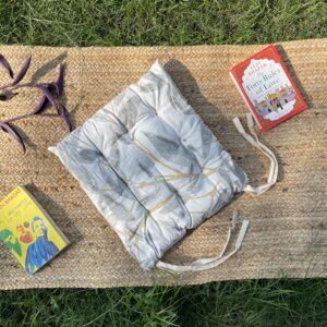 Upcycled chair pad made from repurposed fabrics placed on a mat with books – eco-friendly handmade cushion for sustainable home décor.
