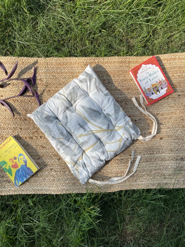 Upcycled chair pad made from repurposed fabrics placed on a mat with books – eco-friendly handmade cushion for sustainable home décor.