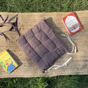 Upcycled chair pad made from repurposed fabrics placed on a mat with books – eco-friendly handmade cushion for sustainable home décor.