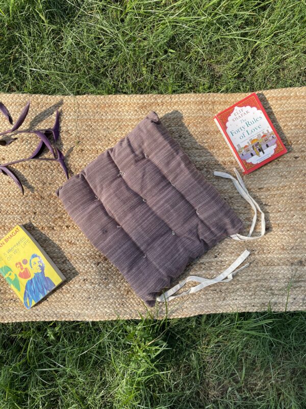 Upcycled chair pad made from repurposed fabrics placed on a mat with books – eco-friendly handmade cushion for sustainable home décor.