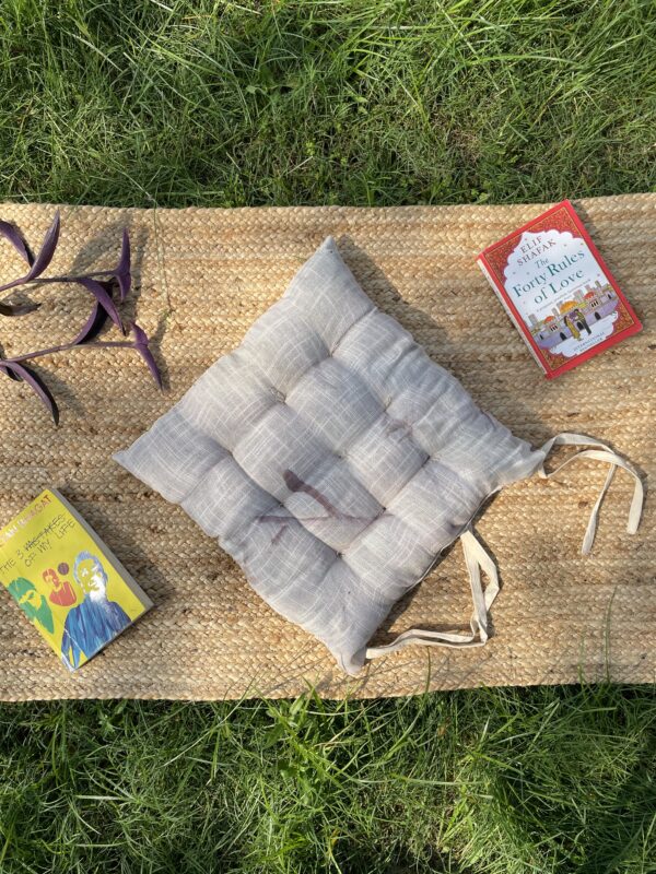 Upcycled chair pad made from repurposed fabrics placed on a mat with books – eco-friendly handmade cushion for sustainable home décor.