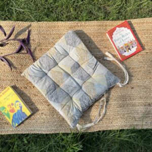 Upcycled chair pad made from repurposed fabrics placed on a mat with books – eco-friendly handmade cushion for sustainable home décor.