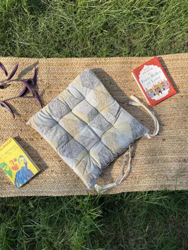 Upcycled chair pad made from repurposed fabrics placed on a mat with books – eco-friendly handmade cushion for sustainable home décor.