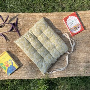 Upcycled chair pad made from repurposed fabrics placed on a mat with books – eco-friendly handmade cushion for sustainable home décor.