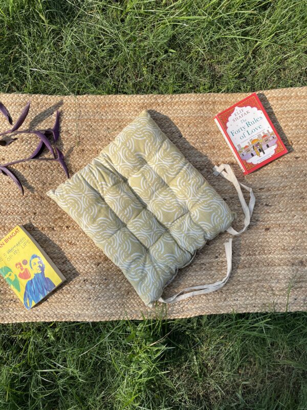 Upcycled chair pad made from repurposed fabrics placed on a mat with books – eco-friendly handmade cushion for sustainable home décor.