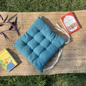 Upcycled chair pad made from repurposed fabrics placed on a mat with books – eco-friendly handmade cushion for sustainable home décor.