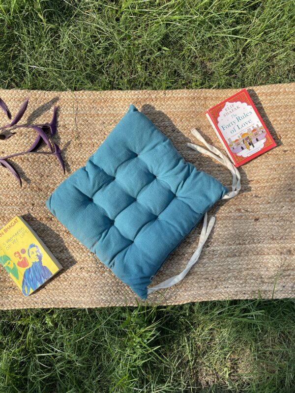 Upcycled chair pad made from repurposed fabrics placed on a mat with books – eco-friendly handmade cushion for sustainable home décor.