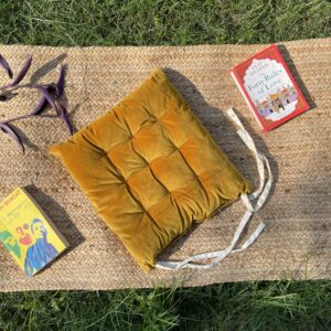 Upcycled chair pad made from repurposed fabrics placed on a mat with books – eco-friendly handmade cushion for sustainable home décor.
