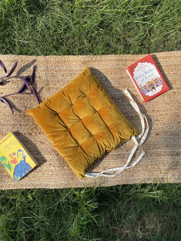 Upcycled chair pad made from repurposed fabrics placed on a mat with books – eco-friendly handmade cushion for sustainable home décor.