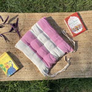 Upcycled chair pad made from repurposed fabrics placed on a mat with books – eco-friendly handmade cushion for sustainable home décor.