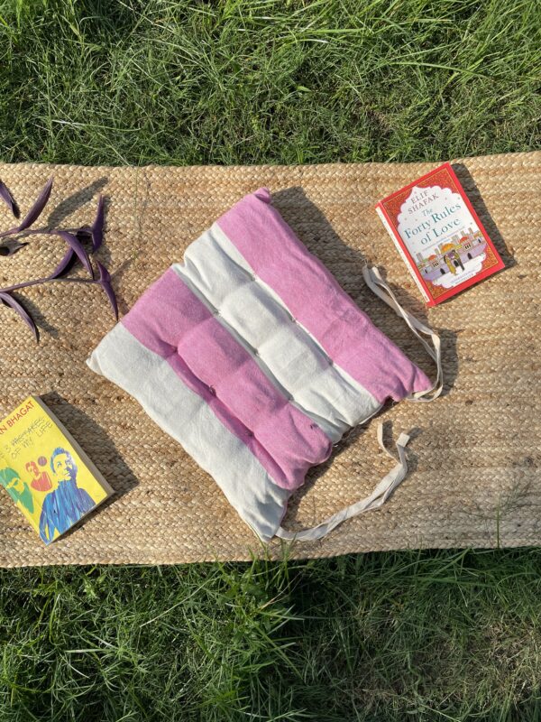 Upcycled chair pad made from repurposed fabrics placed on a mat with books – eco-friendly handmade cushion for sustainable home décor.