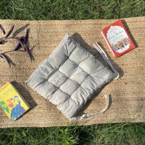 Upcycled chair pad made from repurposed fabrics placed on a mat with books – eco-friendly handmade cushion for sustainable home décor.