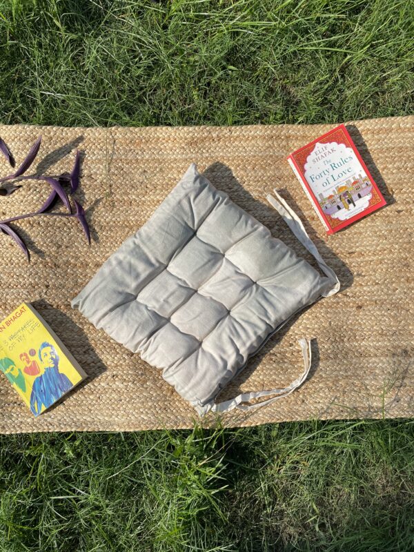 Upcycled chair pad made from repurposed fabrics placed on a mat with books – eco-friendly handmade cushion for sustainable home décor.