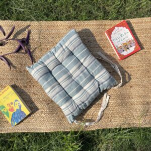 Upcycled chair pad made from repurposed fabrics placed on a mat with books – eco-friendly handmade cushion for sustainable home décor.