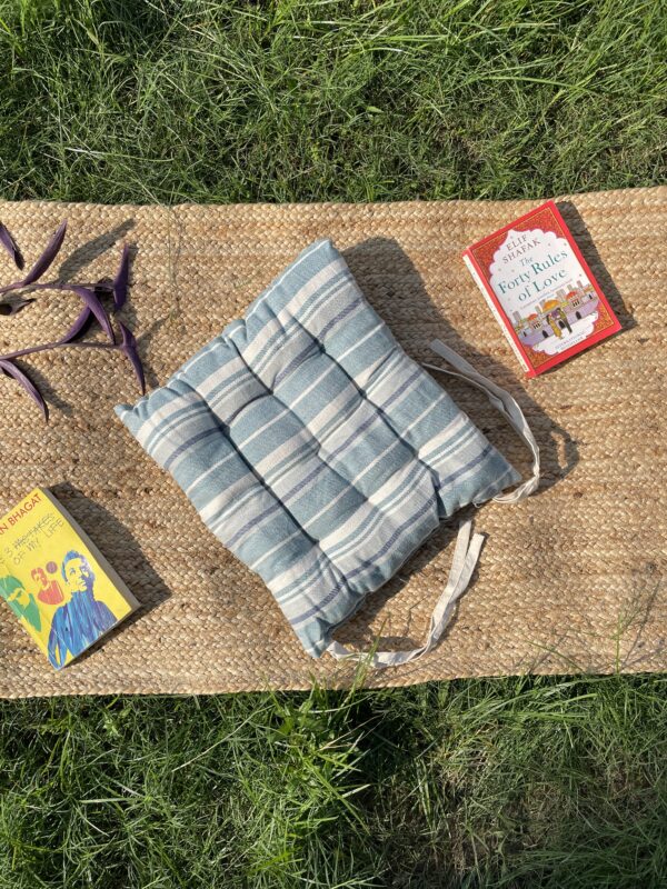 Upcycled chair pad made from repurposed fabrics placed on a mat with books – eco-friendly handmade cushion for sustainable home décor.