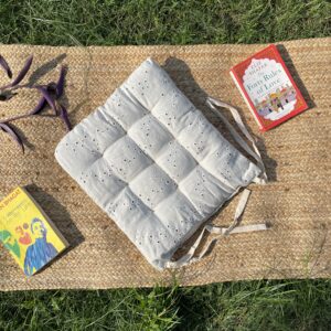 Upcycled chair pad made from repurposed fabrics placed on a mat with books – eco-friendly handmade cushion for sustainable home décor.