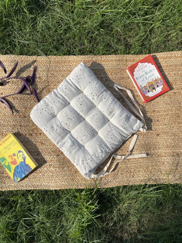 Upcycled chair pad made from repurposed fabrics placed on a mat with books – eco-friendly handmade cushion for sustainable home décor.