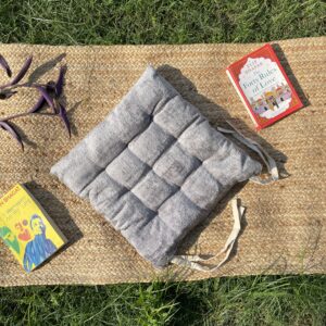 Upcycled chair pad made from repurposed fabrics placed on a mat with books – eco-friendly handmade cushion for sustainable home décor.