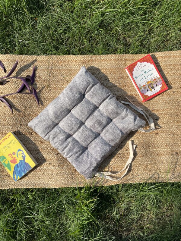 Upcycled chair pad made from repurposed fabrics placed on a mat with books – eco-friendly handmade cushion for sustainable home décor.
