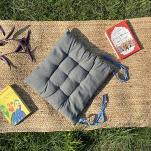 Upcycled chair pad made from repurposed fabrics placed on a mat with books – eco-friendly handmade cushion for sustainable home décor.