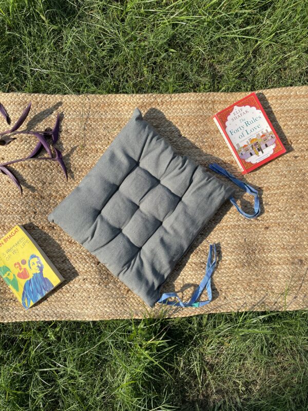 Upcycled chair pad made from repurposed fabrics placed on a mat with books – eco-friendly handmade cushion for sustainable home décor.