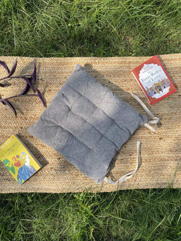 Upcycled chair pad made from repurposed fabrics placed on a mat with books – eco-friendly handmade cushion for sustainable home décor.